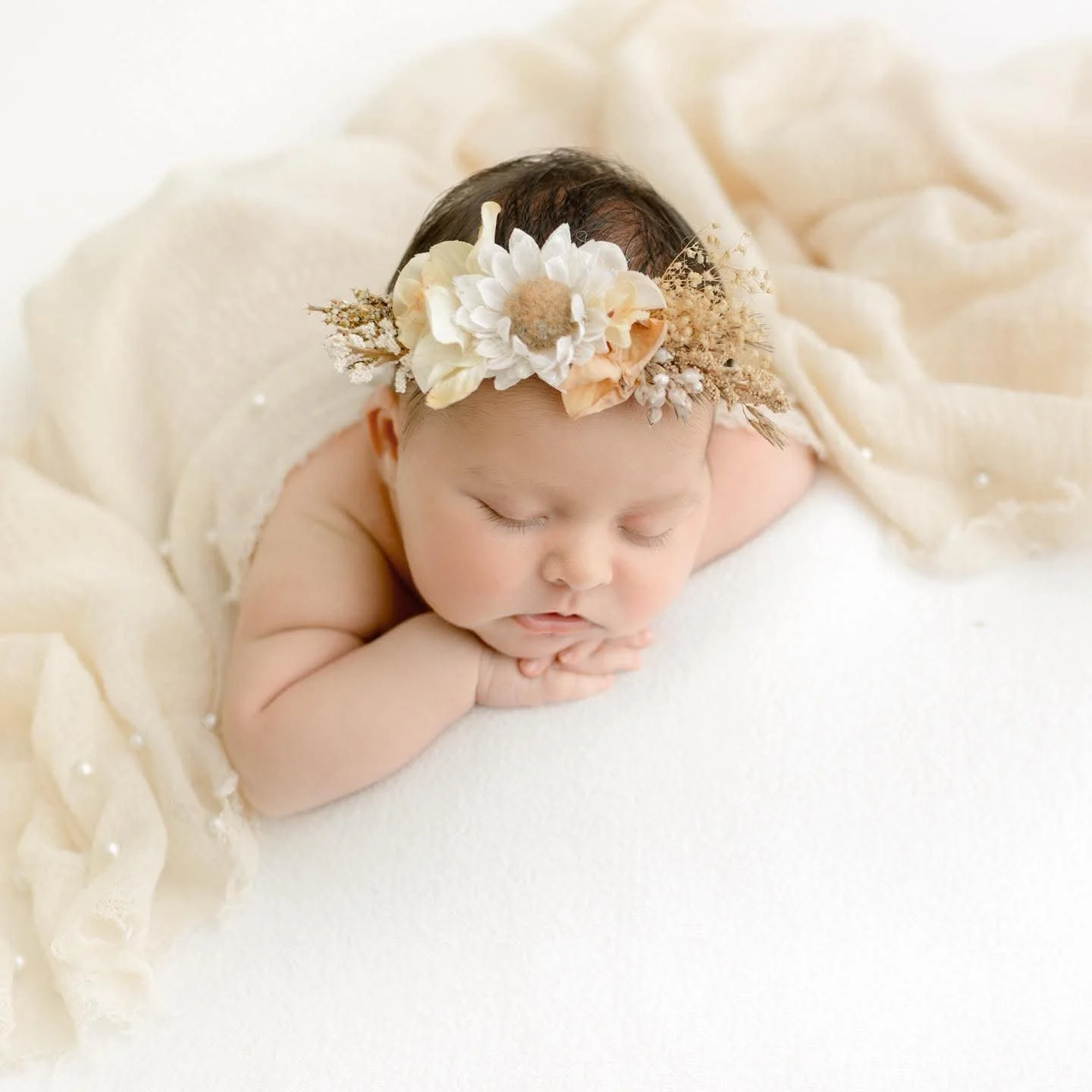 A sleeping newborn wearing a dried-flower crown, photographed in the Syracuse, NY studio
