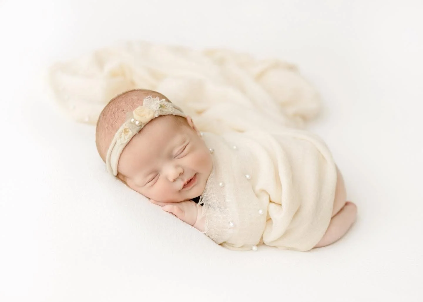Newborn wrapped in soft neutral fabric, photographed in-studio